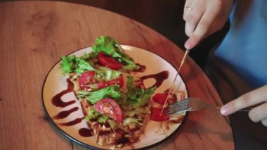 Genç bir kadın sakince pencerede öğle yemeği yiyor, sebzeli sağlıklı bir yemeğin tadını çıkarıyor. İçerde sakin bir ortamda öğle yemeği yiyen bir kadının yakın çekimi.