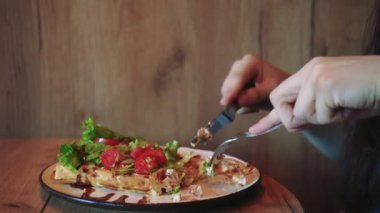 Bir kadın küçük bir masada sağlıklı yemeğinin tadını çıkarırken huzurlu bir yemek anı. Pencereden gelen yumuşak doğal ışık sakin ve rahatlatıcı bir atmosfer yaratıyor.