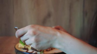 Bir kadın küçük bir masada sağlıklı yemeğinin tadını çıkarırken huzurlu bir yemek anı. Pencereden gelen yumuşak doğal ışık sakin ve rahatlatıcı bir atmosfer yaratıyor.