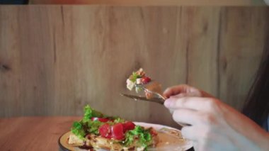 Pencerenin yanında hafif bir yemeğin tadını çıkaran bir kadının olduğu huzurlu bir ev yemeği sahnesi. Sağlıklı gıda ve huzurlu ortam dengeli beslenmenin önemini vurgular