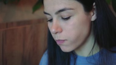 Kapalı alanda rahat bir ortamda yemek yiyen bir kadının yakın çekimi. Doğal ışık, taze sebze yemekten zevk alırken onun düşünceli yüz ifadesini aydınlatıyor.