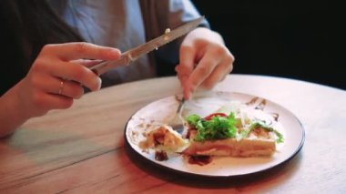 Sakin ve rahat bir an genç bir kadın pencerenin yanında yemeğinin tadını çıkarırken. Tabağındaki taze, sağlıklı maddeler yiyeceğe duyarlı ve dengeli yaklaşımı vurguluyor.