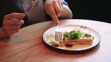 Sakin ve rahat bir an genç bir kadın pencerenin yanında yemeğinin tadını çıkarırken. Tabağındaki taze, sağlıklı maddeler yiyeceğe duyarlı ve dengeli yaklaşımı vurguluyor.