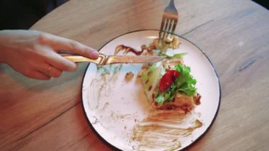 Kapalı alanda rahat bir ortamda yemek yiyen bir kadının yakın çekimi. Doğal ışık, taze sebze yemekten zevk alırken onun düşünceli yüz ifadesini aydınlatıyor.