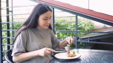 Canlı bir geçmişi olan açık hava yemekleri sağlıklı beslenme ve rahatlama alışkanlıklarını göstermek için mükemmeldir. Dışarıda yemek yiyen genç bir kadının yakın çekimi. Açık havada aydınlık ve sakin bir yer.