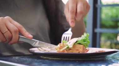 Sağlıklı beslenme ve yaşam tarzını vurgulayan doğal ışıklandırması olan parlak ve sessiz bir açık alan. Çatal ve bıçakla dışarıda taze yemek yiyen bir kadın.