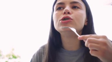 Dışarıda sağlıklı bir yemeğin tadını çıkaran genç bir kadın çatal ve bıçakla yemek yerken tabağına odaklanmış. Arka planda doğal ışık ve yeşillik sakin ve taze bir atmosfer yaratır.