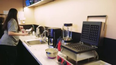 Bu video, temiz ve düzenli bir mutfakta ev yemeği hakkında. Bir kadının marifetli bir şekilde waffle makinesine nasıl vurduğunu ve sonra sağlıklı bir yemek pişirdiğini izleyin.