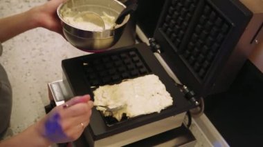 Bir kadının ustalıkla waffle makinesine hamur döküp sonra da sağlıklı bir yemek pişirmesini izleyin. Bu video, temiz ve düzenli bir mutfaktaki ev yemeklerini anlatıyor.