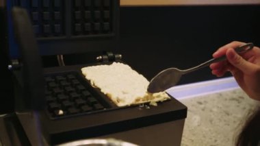 Bir kadının ustalıkla waffle makinesine hamur döküp sonra da sağlıklı bir yemek pişirmesini izleyin. Bu video, temiz ve düzenli bir mutfaktaki ev yemeklerini anlatıyor.
