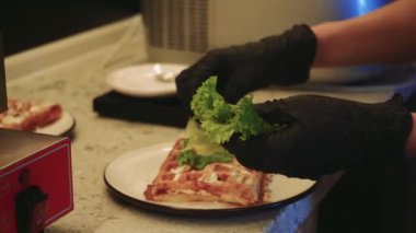 Süreç, ev yemeği ve sağlıklı malzemelerin kombinasyonunu gösteriyor. Genç bir kadın mutfakta lezzetli waffle hazırlıyor, üzerine taze marul ve domates ekliyor.