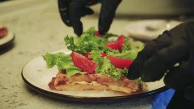 Süreç, ev yemeği ve sağlıklı malzemelerin kombinasyonunu gösteriyor. Genç bir kadın mutfakta lezzetli waffle hazırlıyor, üzerine taze marul ve domates ekliyor.
