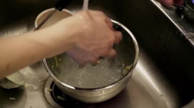 Mutfakta yemek pişirme işlemi. Bir kadın yemek pişirdikten sonra aletleri temizler ve yıkar.