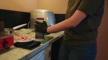 Şef waffle için hamur yoğurur ve tabağa rendelenmiş peynir ve doğranmış jambon ekler. Temiz bir mutfakta ev yapımı tuzlu waffle yapma sanatı üzerine yoğunlaşıldı.