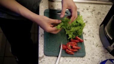 Mutfak lavabosunda sebze yıkayan genç bir kadının yakın çekimi. Yemek pişirme ve yemek hazırlama süreci bir kafede sipariş vermek içindir.