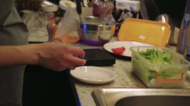 Küçük, rahat bir kafenin mutfağı. Genç bir kız aşçı sebze ve domates hazırlar ve pişmiş yemeği bitirir.