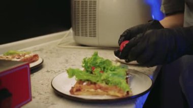 Yeşil salata ve domatesle waffle hazırlayan genç bir kadının detaylı görüntüleri. Görüntü, profesyonel bir mutfakta ev yapımı yemeğin ve düzgün beslenmenin tadını vurguluyor. Yüksek kalite fotoğraf