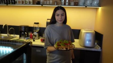 Bir kız taze yeşil yapraklı ve lezzetli kırmızı vişneli domatesli Belçika waffle 'ı gösteriyor. Pastırmalı ve peynirli taze pişmiş tuzlu waffle.