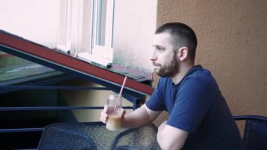 Sükunet anında yakalanan bir adam, içkisiyle yalnız başına dinlenir. Temiz bardak, serinletici içeceği vurguluyor.