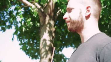 Bu genç adam dışarıda soğuk kokteylinin tadını çıkarıyor. Yaz ağaçlarıyla çevrili, rahatlama ve ferahlamanın özünü kucaklıyor.