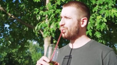 Serinletici bir içkinin tadını çıkaran bu genç adam dışarıda huzuru buluyor. Güzel yaz manzarası rahatlatıcı bir an için ideal bir ortam sağlar.