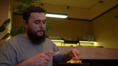 Elleri taze marul ve domatesle bir tabağı kesiyor, sıradan bir yemek ortamında servis ediliyor. Yakın plan, canlı yiyecekleri ve sade, sade sunumu vurguluyor. Sağlıklı ve keyifli bir sunumu vurguluyor.