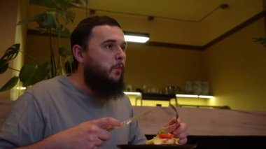 Elleri taze marul ve domatesle bir tabağı kesiyor, sıradan bir yemek ortamında servis ediliyor. Yakın plan, canlı yiyecekleri ve sade, sade sunumu vurguluyor. Sağlıklı ve keyifli bir sunumu vurguluyor.