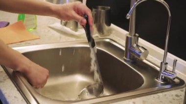 Mutfakta akan suyun altında metal lavabo yıkayan elleri yakından çek. Odak noktamız temizlik ve temizlik.