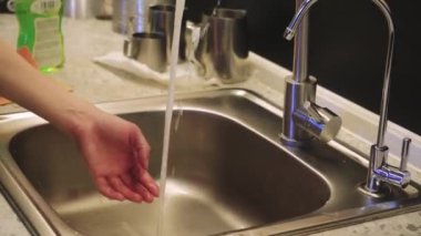 Mutfakta akan suyun altında metal lavabo yıkayan elleri yakından çek. Odak noktamız temizlik ve temizlik.