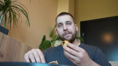 Bir adam sıcak bir kruvasana saldırıyor, kokunun ve tadının tadını çıkarıyor. Video, pastanın yumuşak katmanlarını ve lezzetli ısırığını vurguluyor.