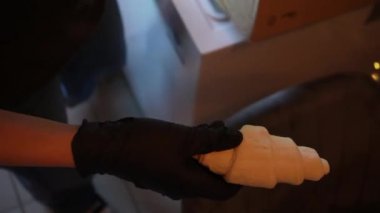 Siyah nitril eldivenli genç bir kadın dondurucudaki mavi bir çantadan donmuş kruvasan hamuru çıkarıp yeni bir yığın hamur işi için hazırlanıyor.