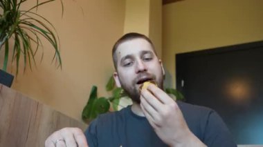 Bir adam sıcak bir kruvasana saldırıyor, kokunun ve tadının tadını çıkarıyor. Video, pastanın yumuşak katmanlarını ve lezzetli ısırığını vurguluyor.