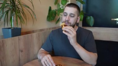 Çikolatayla kaplı taze kruvasanın tadını çıkaran genç bir adam bu pastanın tazeliğini ve kokusunu aktarıyor.