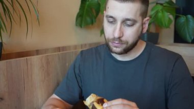 Çikolatayla kaplı taze kruvasanın tadını çıkaran genç bir adam bu pastanın tazeliğini ve kokusunu aktarıyor.