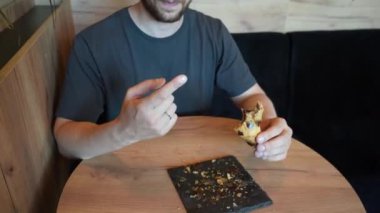 Bu sahnede bir kruvasan var. Elinde bir parça hamur işi tutan genç bir adam var. Video, taze pişmiş hamurun cazibesini taşıyor.