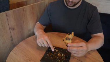 Bu sahnede bir kruvasan var. Elinde bir parça hamur işi tutan genç bir adam var. Video, taze pişmiş hamurun cazibesini taşıyor.