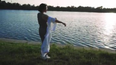 Etrafı yeşilliklerle çevrili bir kadının nehir boyunca sessiz bir yürüyüş yaptığı sakin bir sahne. Doğa, yaşam tarzı ve rahatlama temalı görseller için mükemmel.