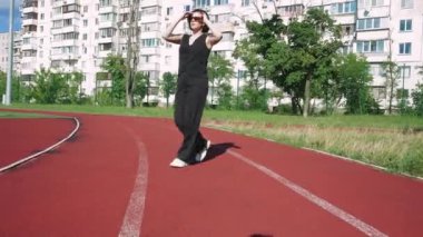 Spor sahası olan bir apartman kompleksinin yanından geçen güneş gözlüklü genç bir kadın avlunun huzuru ile çevrili bir şekilde düşüncelere daldı..