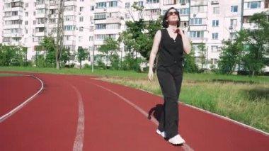 Spor sahası olan bir apartman kompleksinin yanından geçen güneş gözlüklü genç bir kadın avlunun huzuru ile çevrili bir şekilde düşüncelere daldı..