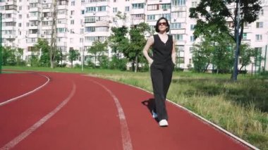 Spor sahası olan bir apartman kompleksinin yanından geçen güneş gözlüklü genç bir kadın avlunun huzuru ile çevrili bir şekilde düşüncelere daldı..