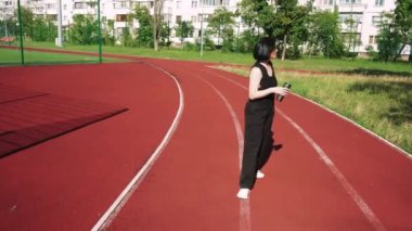 Bir apartmanın arka planında, elinde bir fincan çayla düşünen bir kız. Spor sahası olan iç saha
