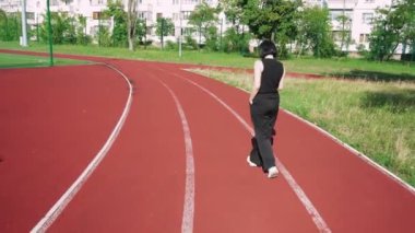 Bir apartmanın arka planında, elinde bir fincan çayla düşünen bir kız. Spor sahası olan iç saha