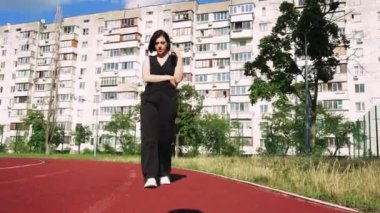 Bir apartmanın arka planında, elinde bir fincan çayla düşünen bir kız. Spor sahası olan iç saha