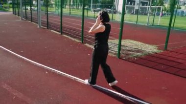 Çevresi apartmanlarla çevrili yeşil bir şehir parkında kırmızı bir yolda yürüyen bir kadın. Kentsel yaşam tarzı ve açık hava etkinlik temaları için harika