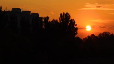 Parkın ve su deposunun üzerinde gün batımı. Turuncu ve siyah gölgeli heyecan verici bir olay. Akşam güneşinin güzel bir manzarası
