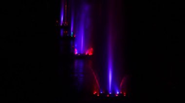 Renkli çeşmeler. Karanlık arka plan. Büyük renkli dekoratif dans jeti geceleri hafif fıskiye gösterisine öncülük etti. Güzel lazer ve fıskiye gösterisi