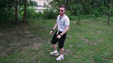 Gömlek ve şort giyen şık bir adam bitkilerle dolu yeşil bir bölgeyi keşfediyor. Sahne sakin bir ortamda rahatlamaya, doğaya ve kişisel yansımaya odaklanıyor.