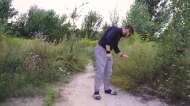 Genç bir adam koyu yeşil bir tişörtle sık ve yeşil bir arazide geziniyor. Doğadaki sakin ve huzurlu bir anı yakalamak, yalnızlık, farkındalık ve açık hava yaşam tarzı kavramları için idealdir.