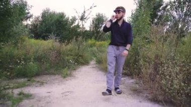 Genç bir adam koyu yeşil bir tişörtle sık ve yeşil bir arazide geziniyor. Doğadaki sakin ve huzurlu bir anı yakalamak, yalnızlık, farkındalık ve açık hava yaşam tarzı kavramları için idealdir.