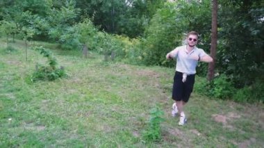 Koyu renk tişörtlü bir adam yemyeşil, fazla gelişmiş bir bölgeyi keşfediyor. Yeşillikte yavaşça yürüyor, doğada sakin bir sahne yaratıyor. Macera, rahatlama ve yalnızlık temaları için mükemmel.